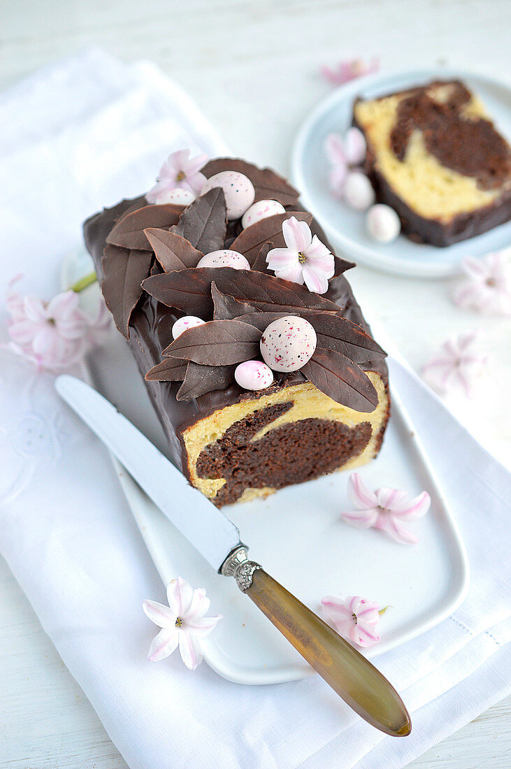 Marmorkuchen mit Schokoladenblättern, Zuckereiern und Hyazinthenblüten, angeschnitten