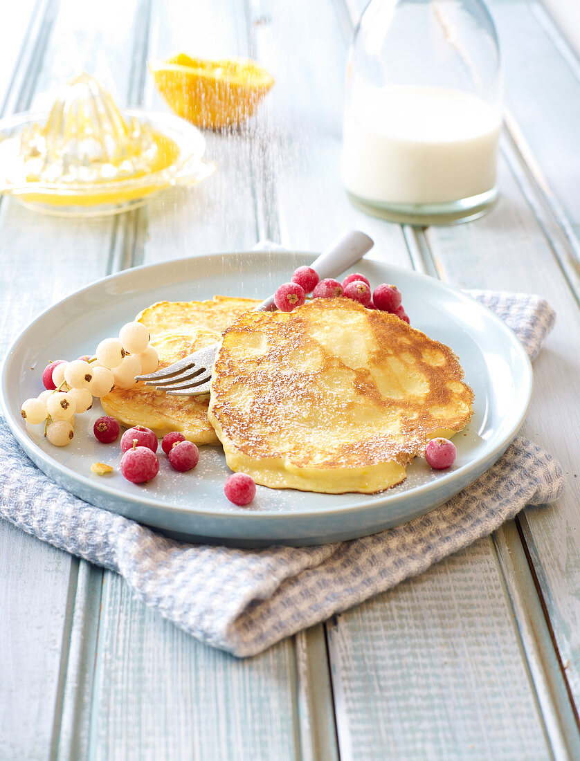 Icing sugar sprinkled on ricotta and red currant pancakes