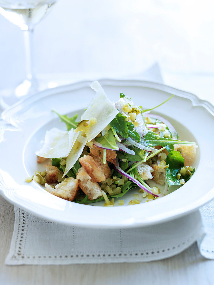 Rucolasalat mit Knoblauchcroutons, roten Zwiebeln und Essiggurken