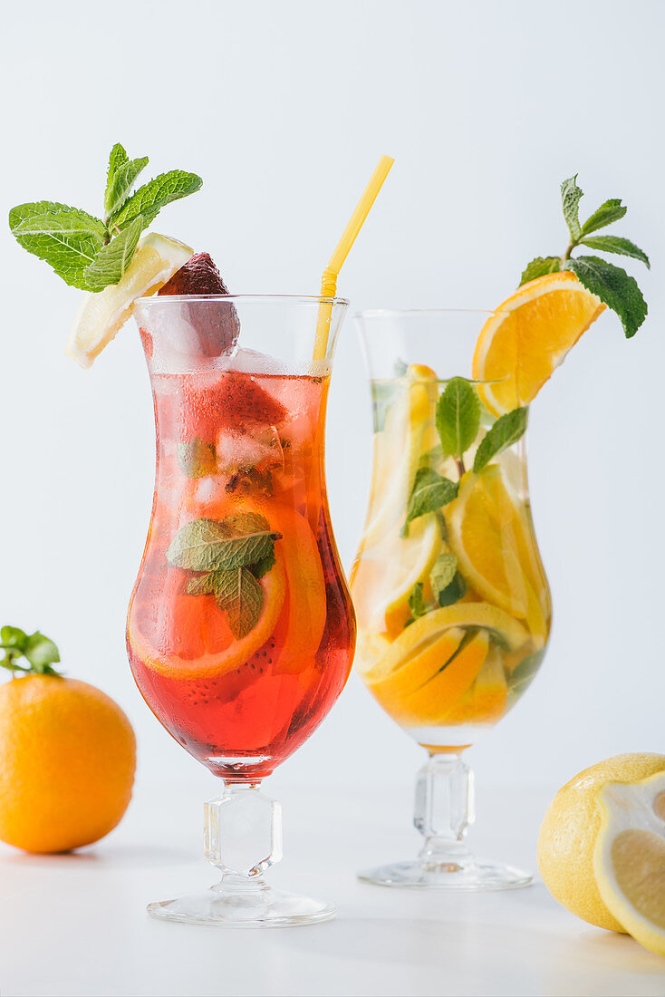Summer fresh cocktails with strawberry, lemon and orange pieces, mint isolated on white