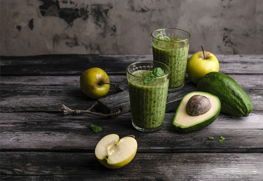 Two glasses of apple-avocado smoothie on wooden table