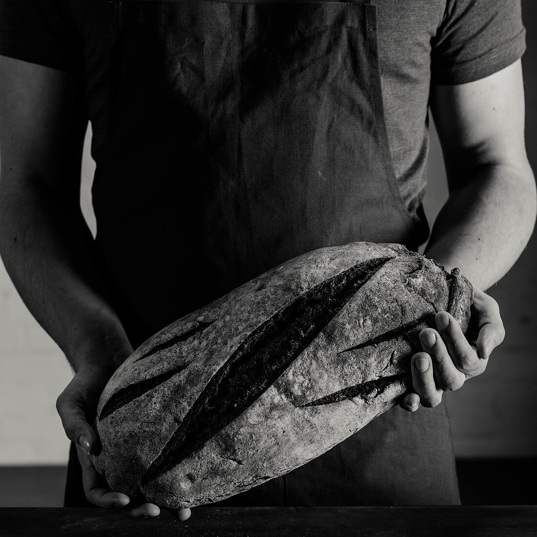 Baker holding bread in his hands (black and white photo)