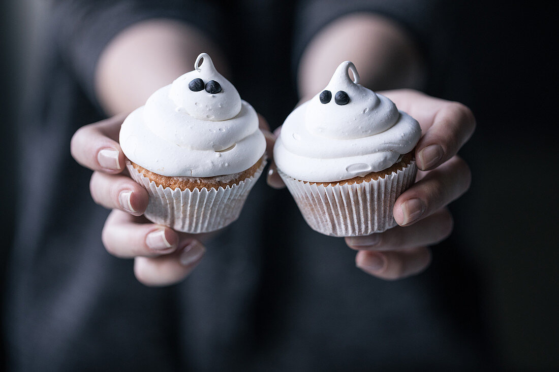Hände halten Halloween-Muffins