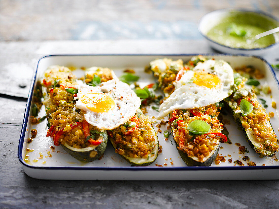 Stuffed zucchini with quinoa, corn, peppers and fried eggs
