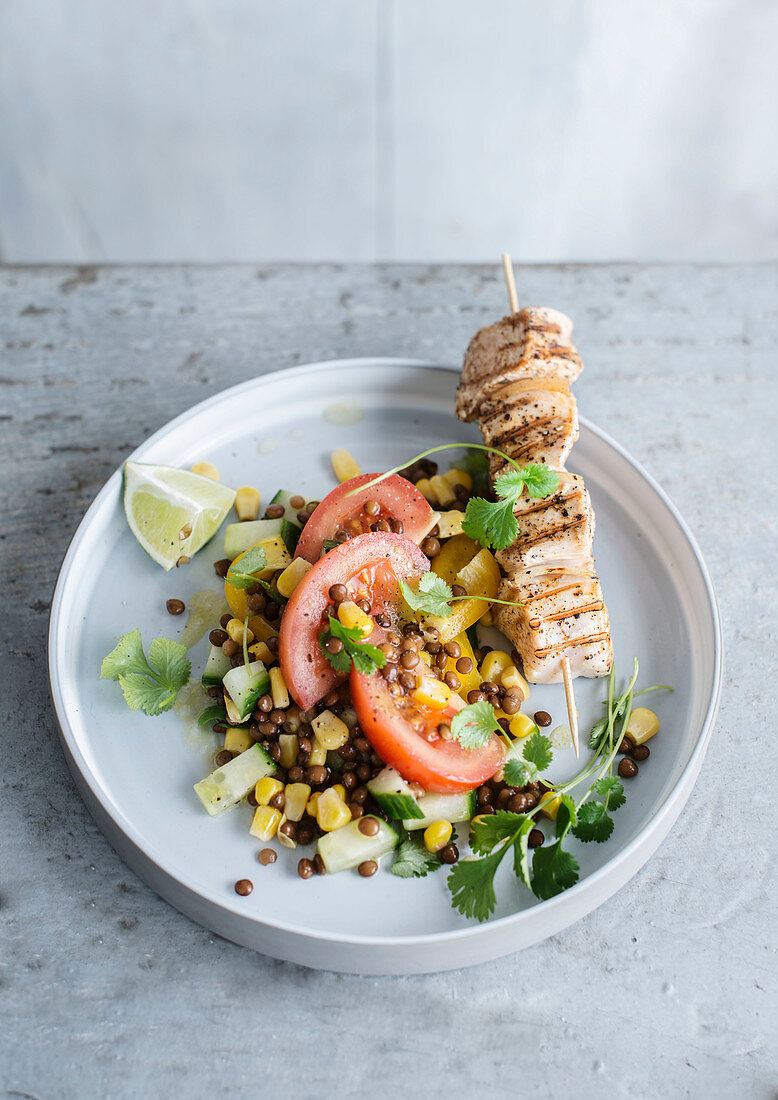 Chicken skewer with lentil salad with corn, cucumber and tomatoes