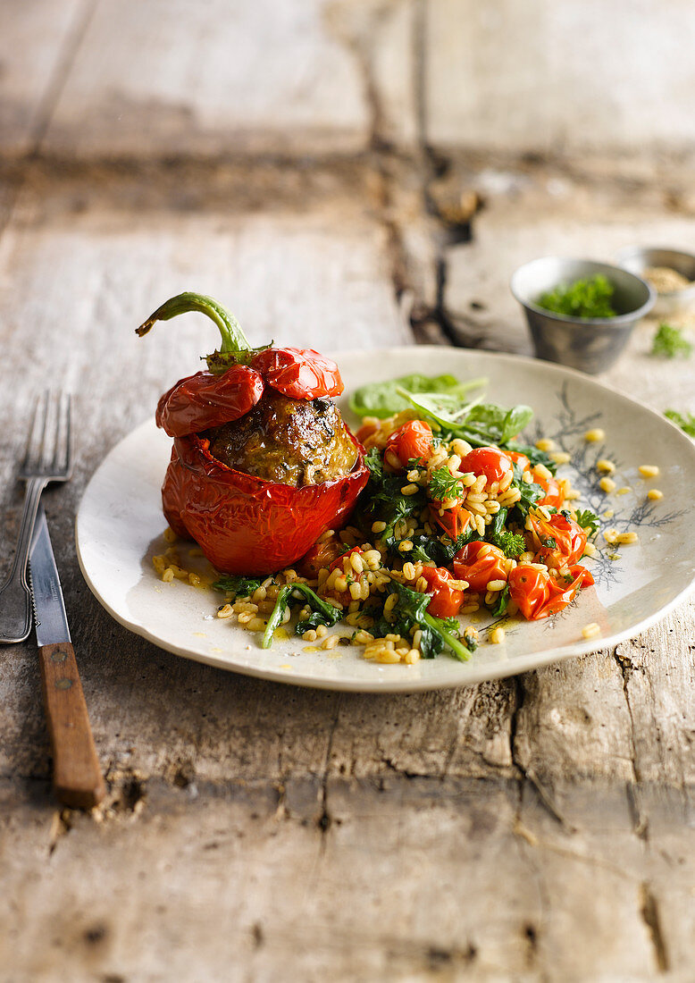 Stuffed peppers served with wheat with spinach and cherry tomatoes