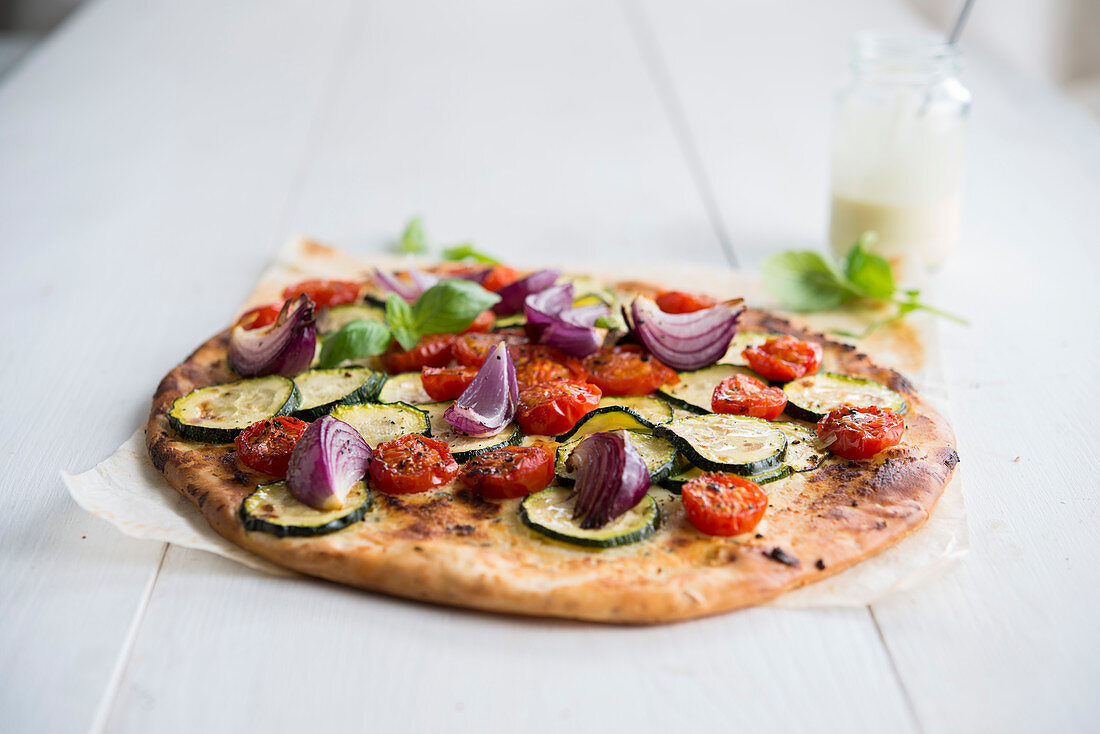 Veggie-Pizza mit Tomaten, Zucchini und roten Zwiebeln