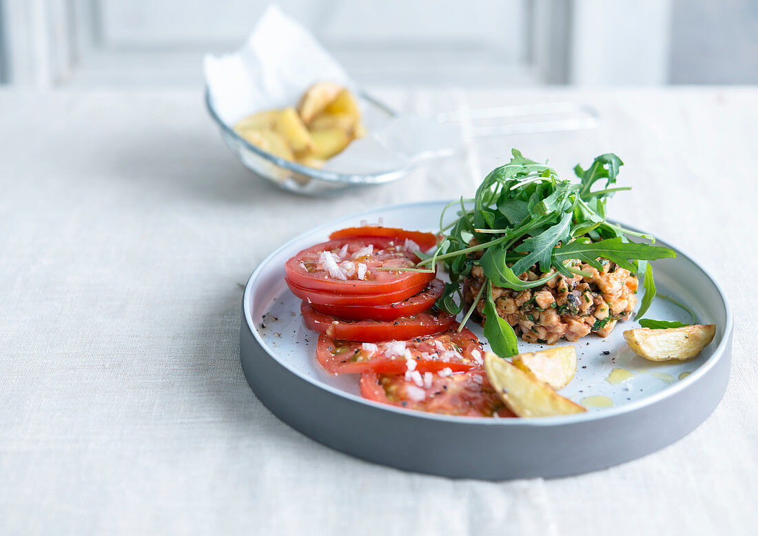 Vegetable tartare with rocket, tomatoes and potato wedges
