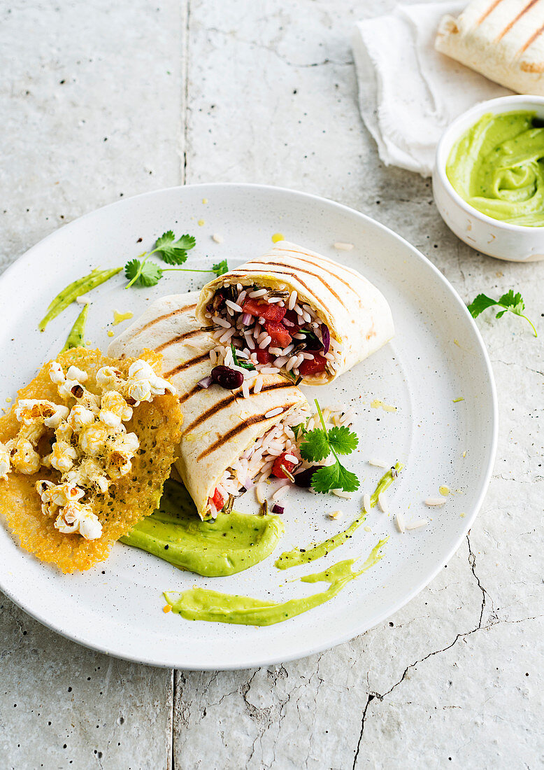 Burrito filled with rice salad served with guacamole and popcorn