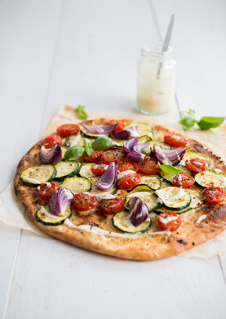 Pizza mit Zucchini, Kirschtomaten und roten Zwiebeln