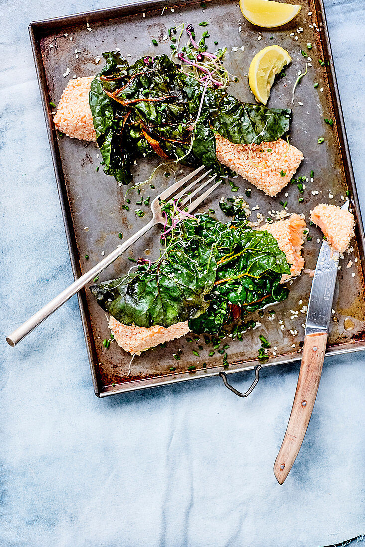 Salmon fillets in a sesame crust with chard on a baking tray