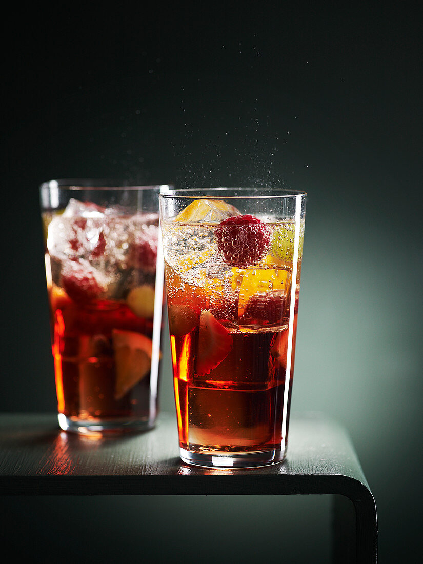 Zwei Cocktails mit Früchten und Eiswürfeln