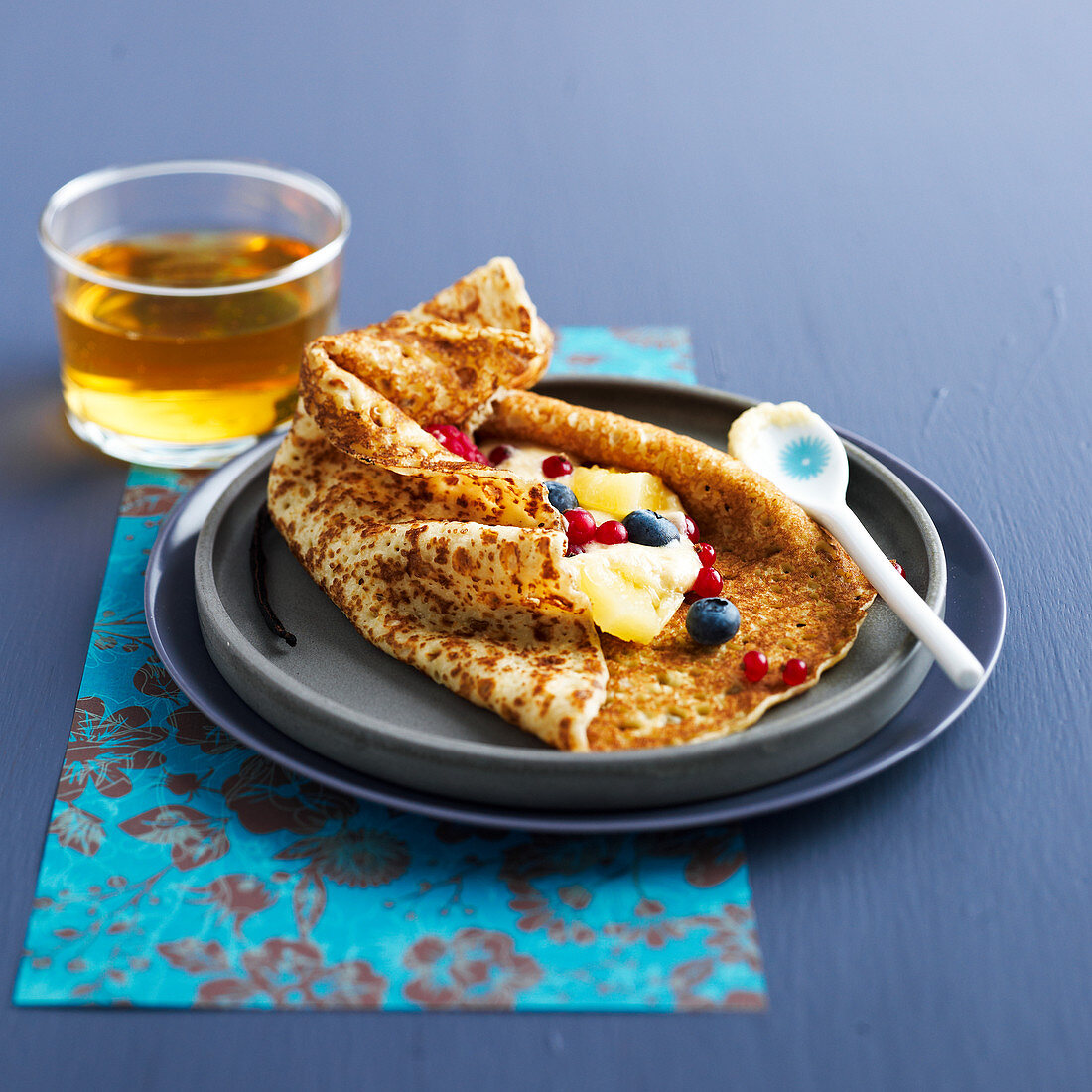 Crepe filled with pineapple and berries, served with a glass of cider