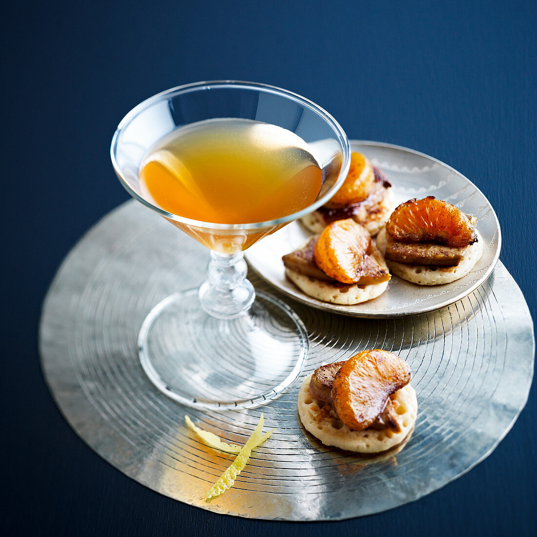 Sunset cocktail served with mini blinis with foie gras and mandarin segments