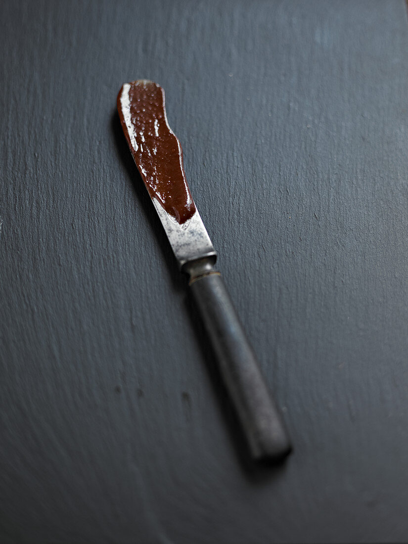 Messer mit Resten von geschmolzener Schokolade auf dunklem Untergrund