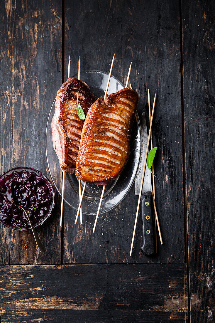 Grilled whole duck breasts on skewers with cherry chutney