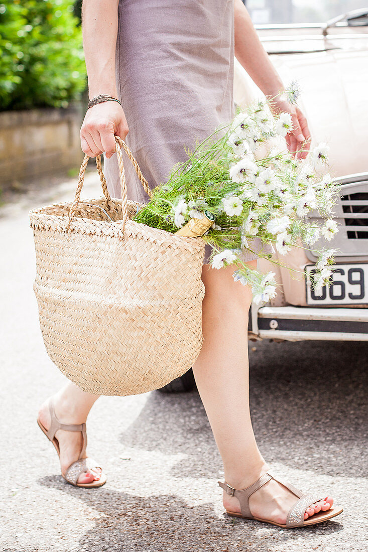 Frau mit Blumenstrauß in Einkaufskorb