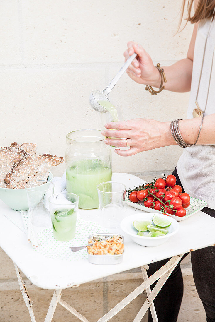 Woman pouring lime-mint lemonade into glasses