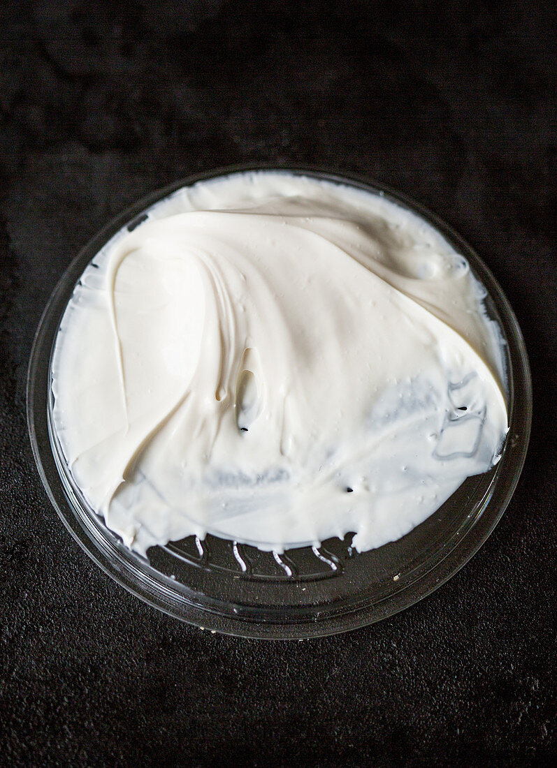 Crème-Fraîche-Reste auf Plastikdeckel