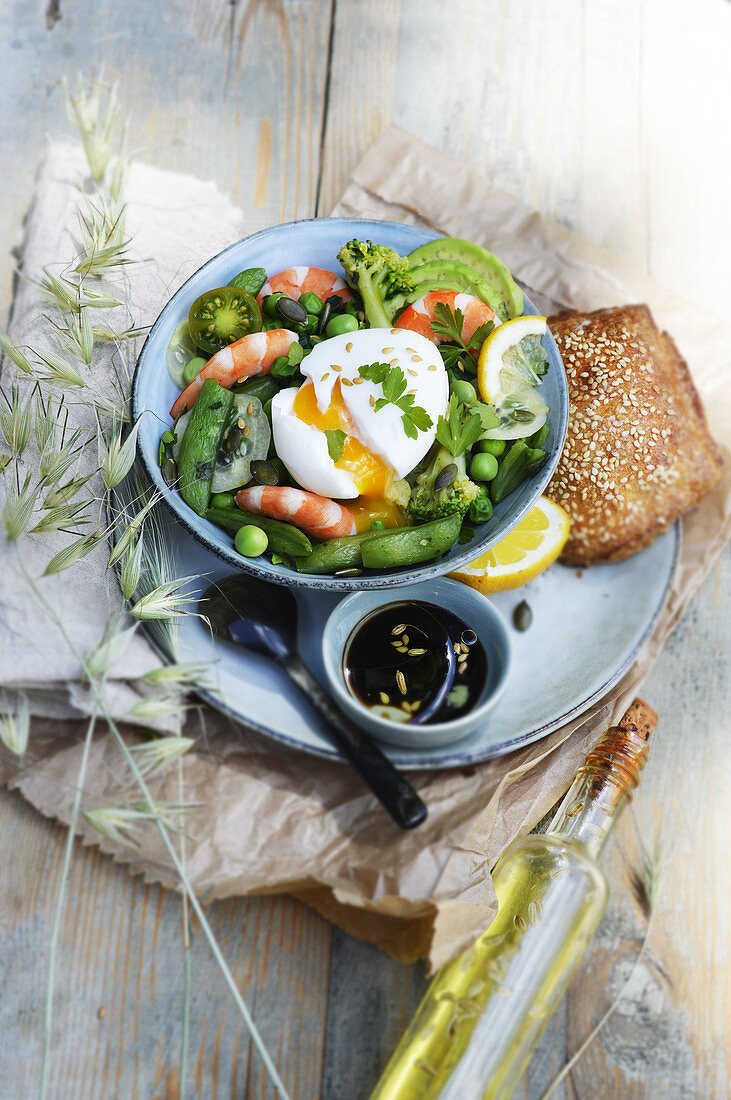 Bowl with green vegetables, prawns and a soft-boiled egg