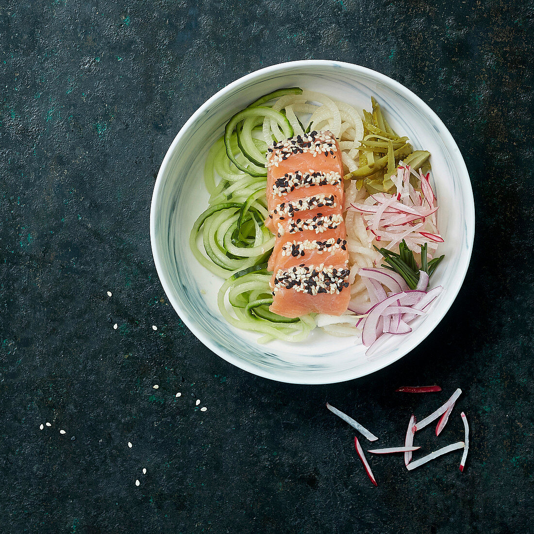 Sesame salmon sashimi with vegetable spaghetti made of courgette, cucumber, onion and radish