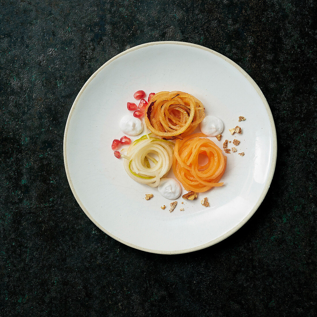 Sweet ‘spaghetti’ nests made of melon, apple and pear with almond cream and pomegranate seeds