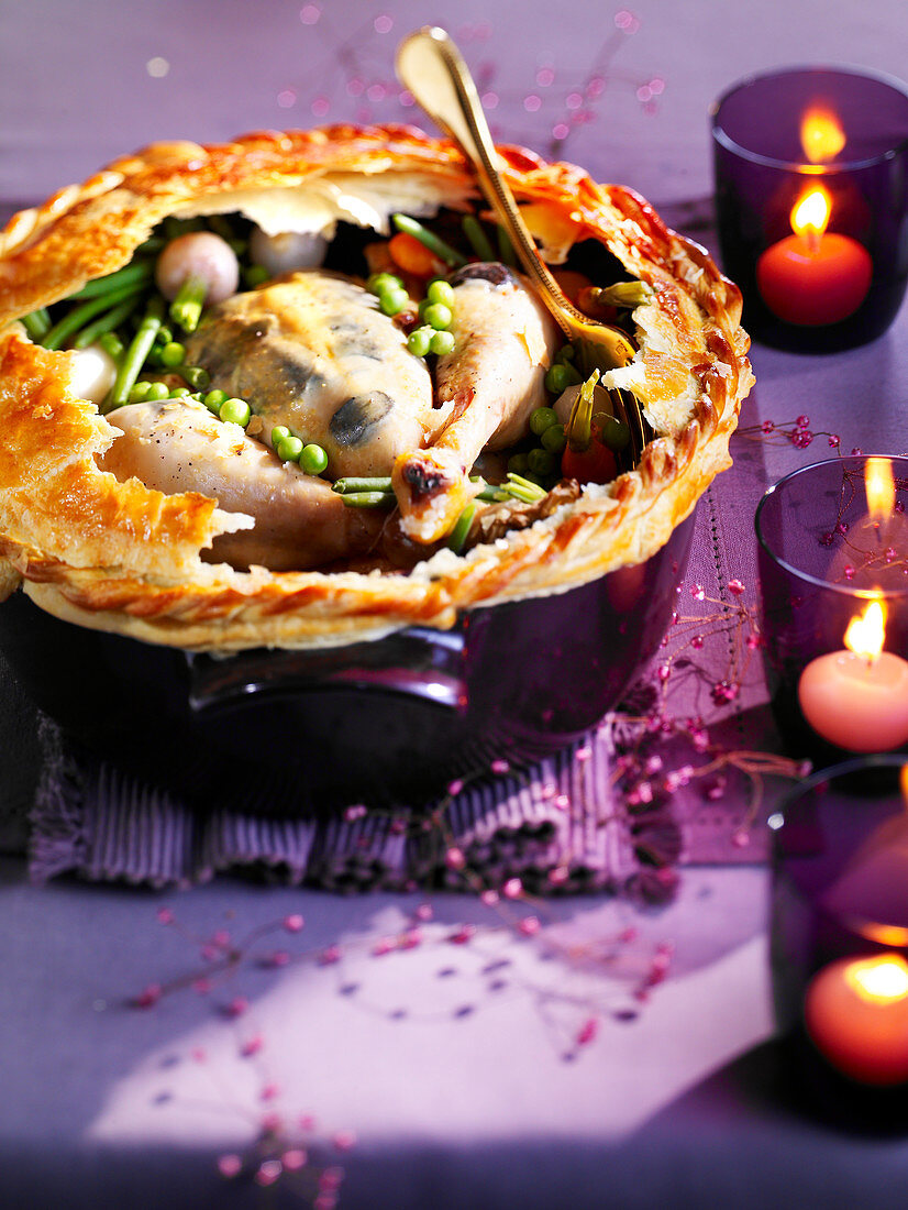 Festive capon with spring vegetables under a puff pastry top