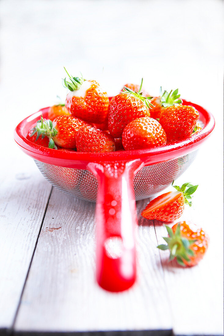 Fresh strawberries in a red colander
