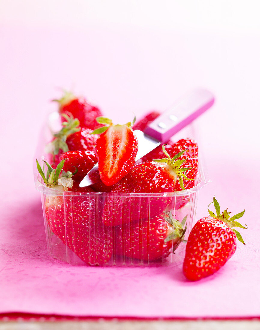 Erdbeeren mit Messer in Plastikschale