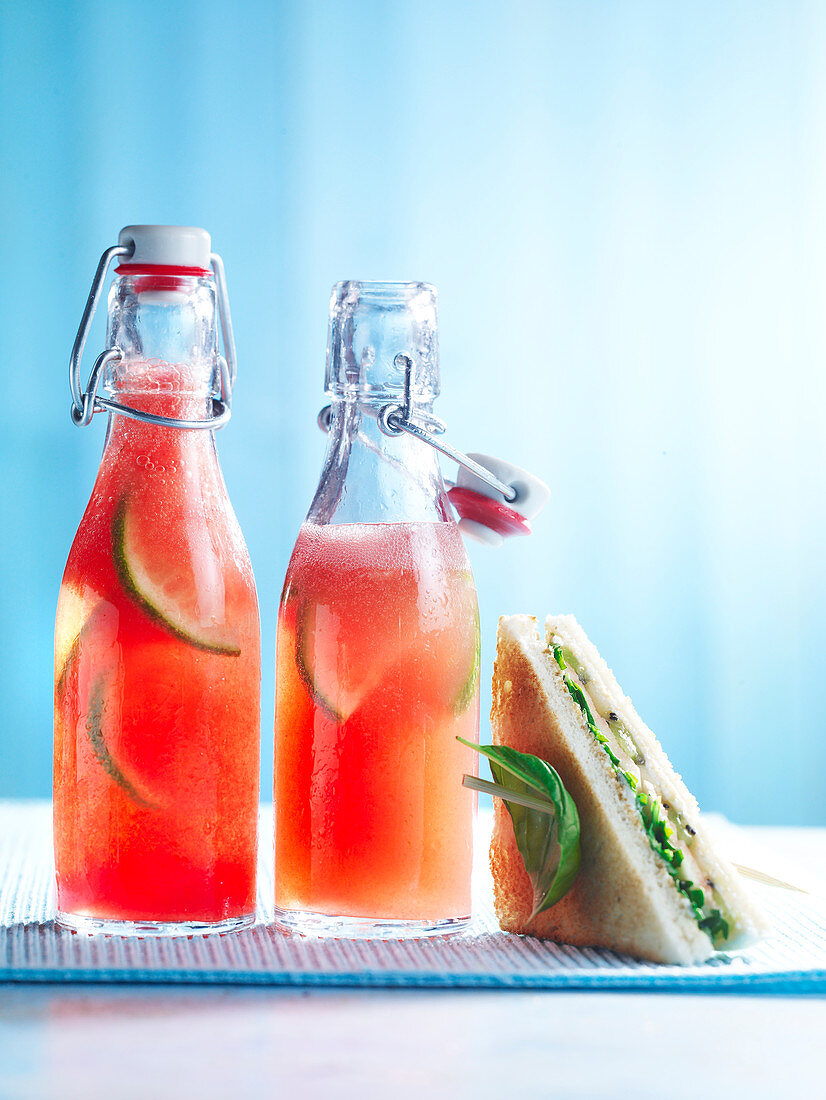 Watermelon lemonade in bottles, next to a sandwich
