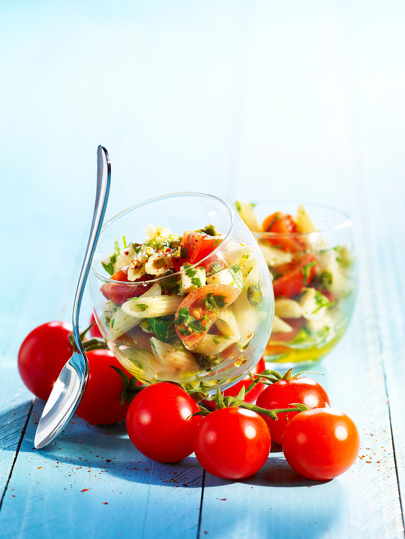 Pasta salad with penne, smoked salmon and cherry tomatoes in glass bowls