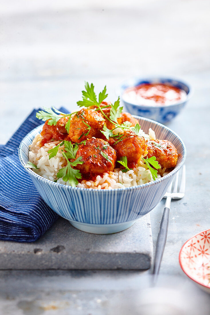 Meatballs in tomato sauce and chervil on rice