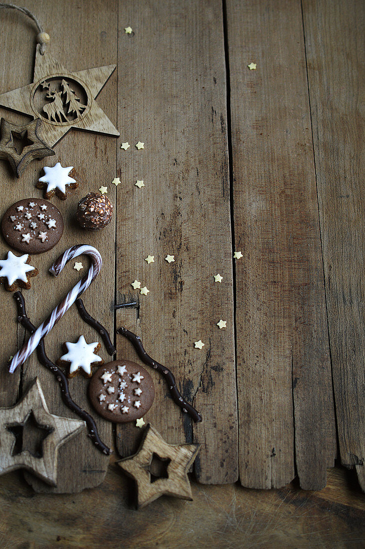 Wooden stars, Christmas biscuits and a candy cane on a wooden background