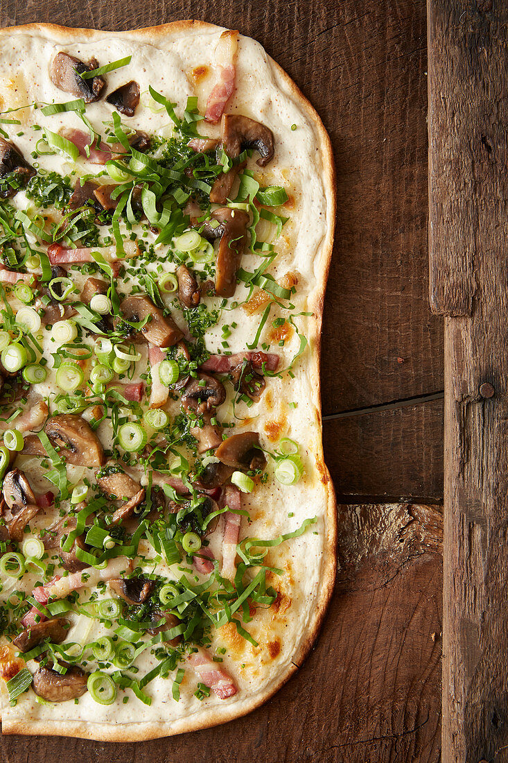 White pizza with mushrooms, bacon and spring onions