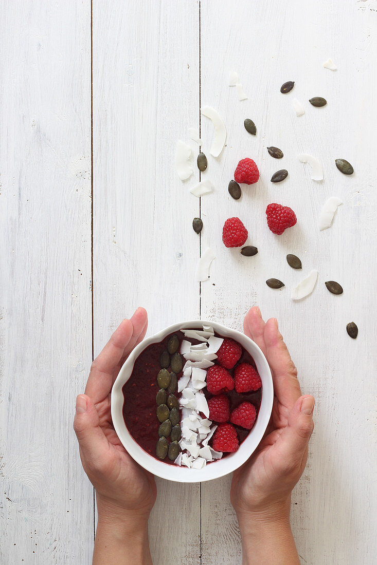 Smoothie bowl with coconut, raspberries and pumpkin seeds
