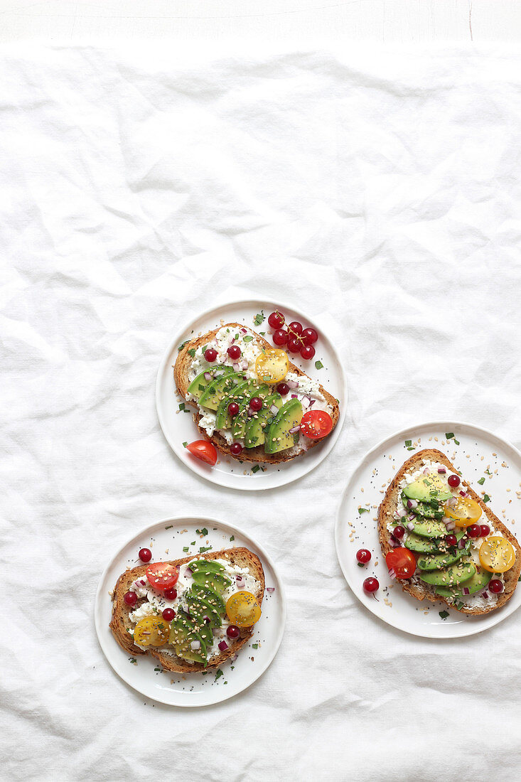 Sandwiches topped with cream cheese, avocado and colourful cherry tomatoes
