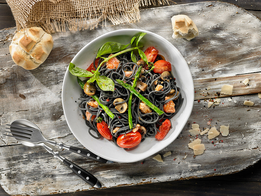 Black spaghetti with salmon, tomatoes and mushrooms