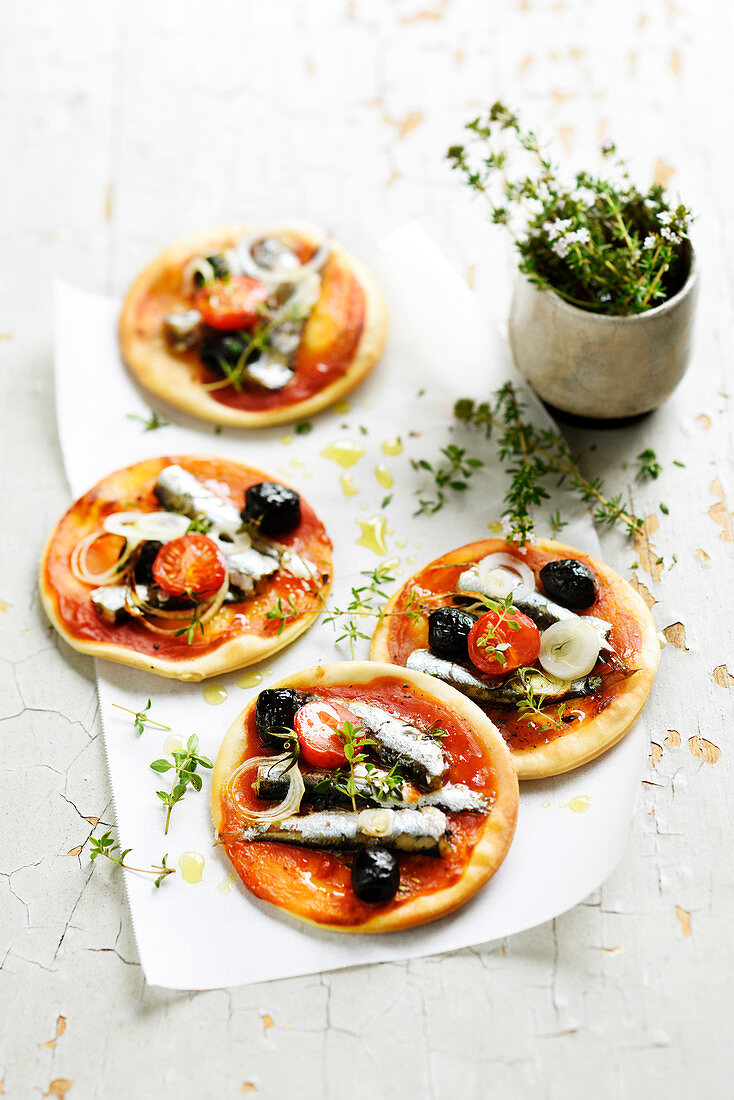 Mini pizzas with sardines, tomatoes, onions and olives