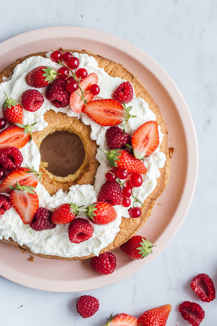 Ringförmiger Geburtstagskuchen mit Sahne und roten Beeren