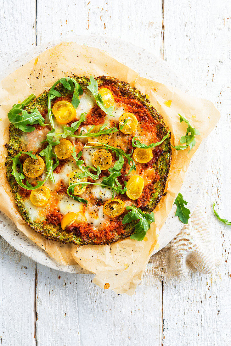 Broccoli pizza with mozzarella, yellow cherry tomatoes and rocket salad