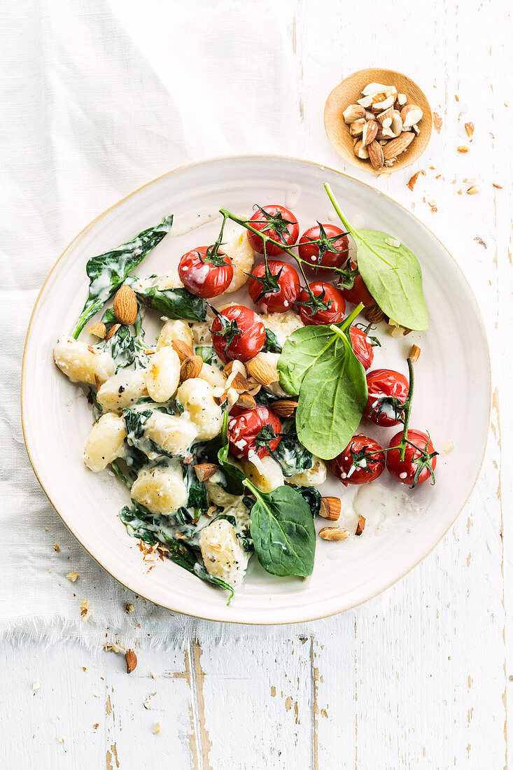 Gnocchi with cherry tomatoes, spinach, melted cheese and herbs