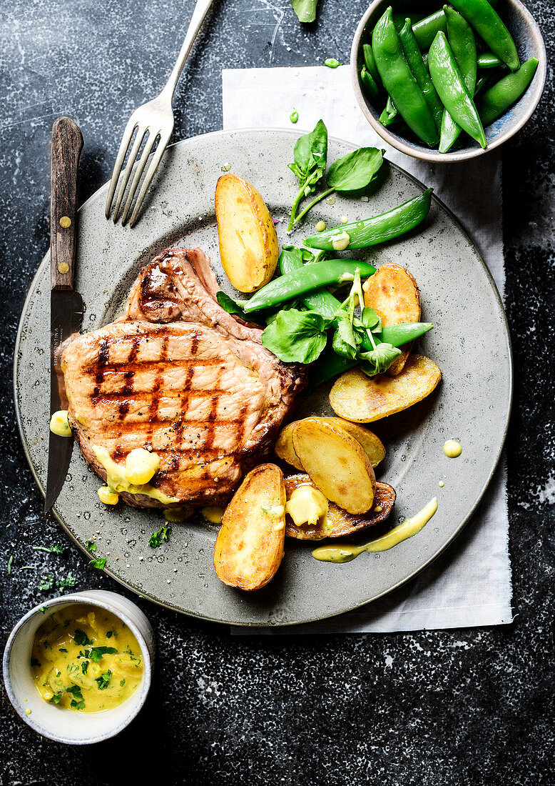 Grilled pork chop with potatoes, sugar snap peas, and cucumber sauce