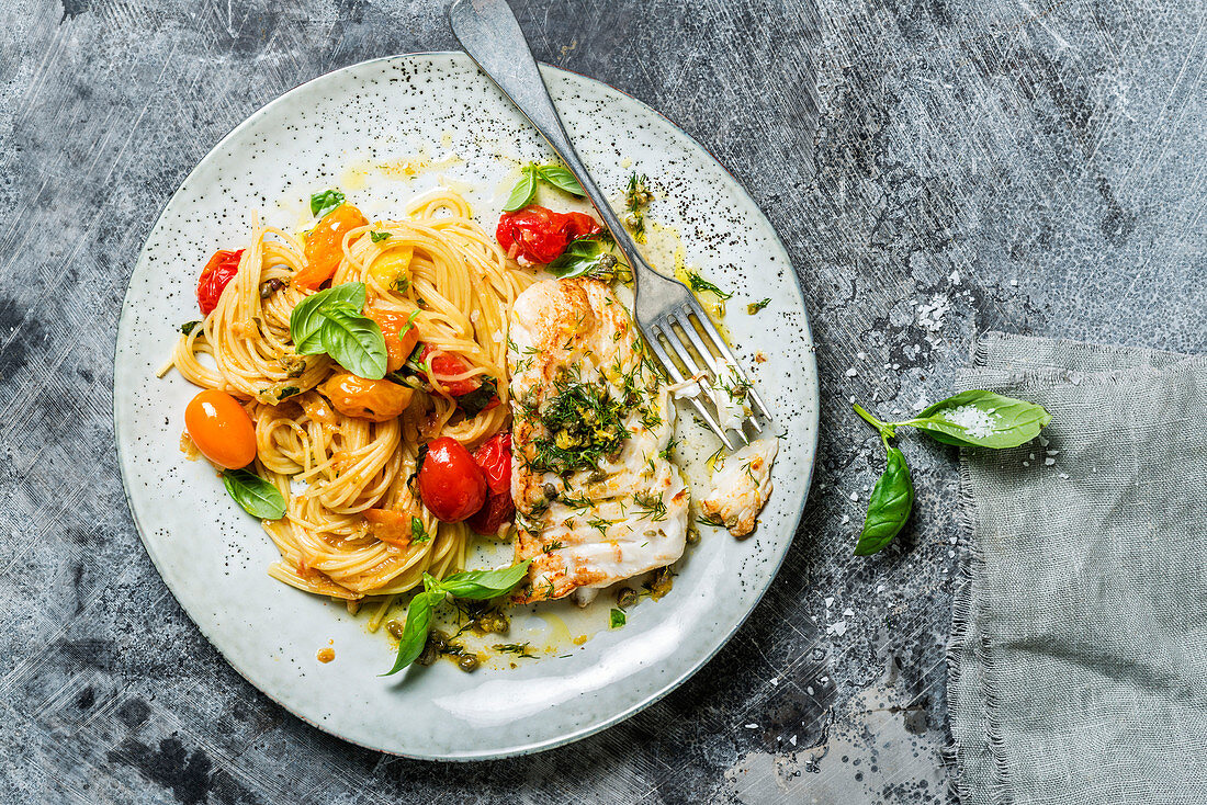 Fish fillet and spaghetti with cherry tomatoes and basil