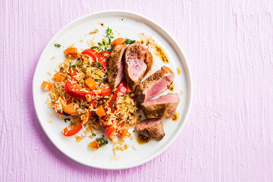 Pork tenderloin served with fried rice and vegetables