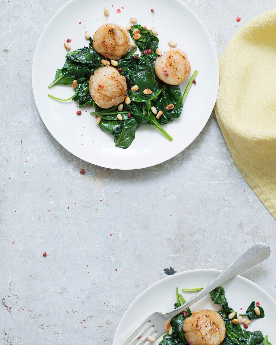 Fried scallops on spinach leaves with pine nuts