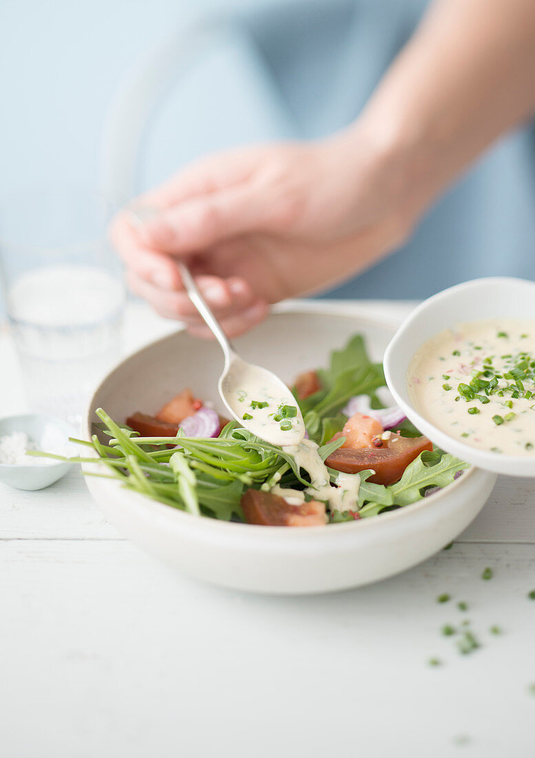 Schmelzkäse-Vinaigrette auf Tomaten-Rucola-Salat verteilen