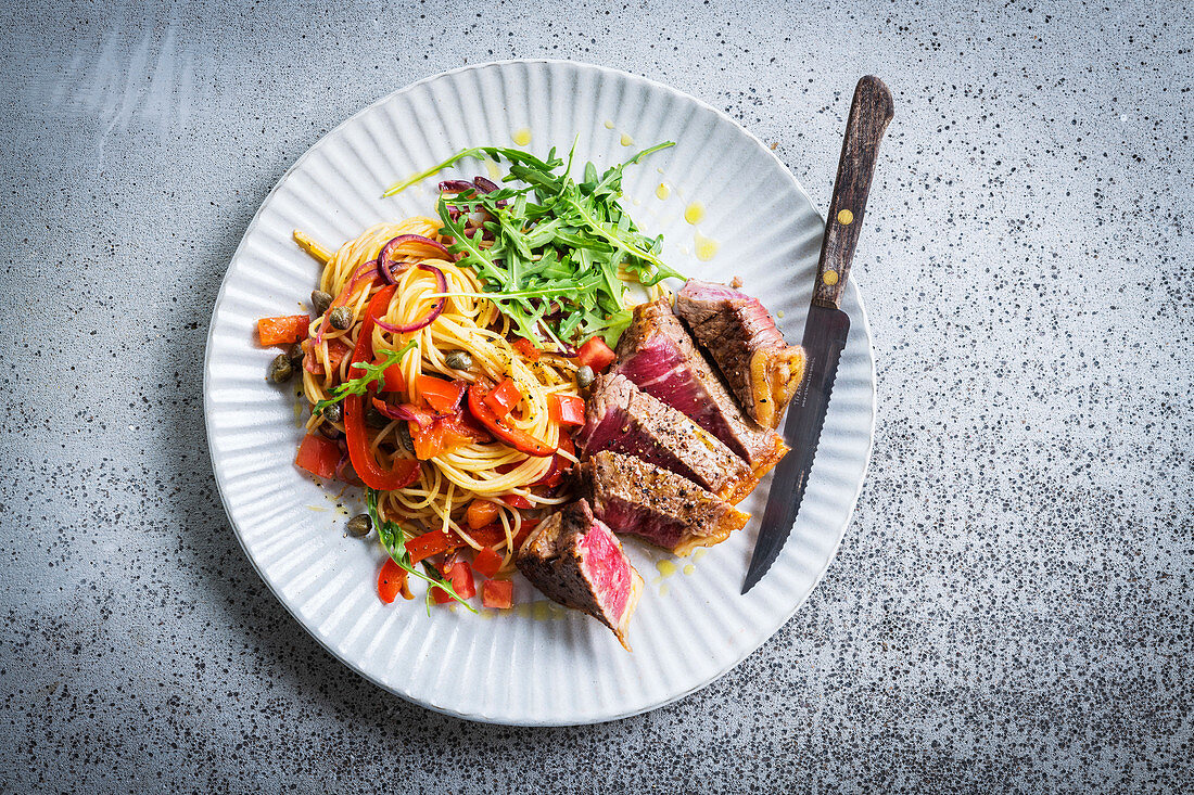 Pepper steak, served with spaghetti with peppers, tomatoes and capers
