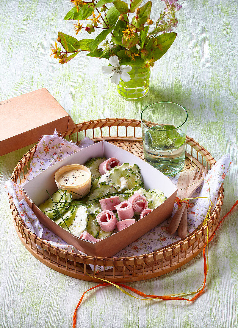 Bento box with cucumber salad and ham rolls