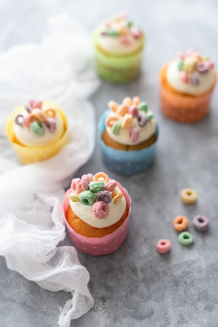 Cupcakes with frosting and topped with multicolored cereals