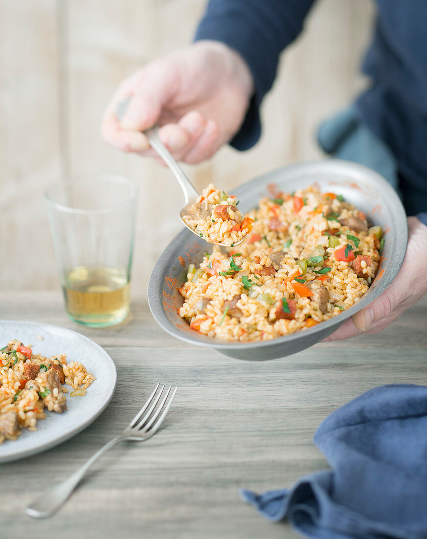 Person serves rice with chorizo